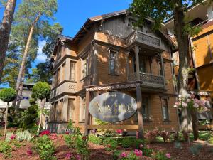 un bâtiment avec un panneau devant lui dans l'établissement Villa Alvīne Family Apart-Hotel, à Jurmala