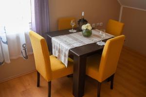 a dining room table with yellow chairs and a table with wine glasses at Golden BIS, Subotica in Subotica