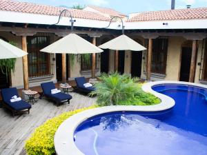 a pool with chairs and umbrellas next to a building at Camino Real Antigua in Antigua Guatemala