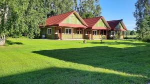 una casa con tetto rosso e un ampio cortile di Wiśniowy Sad - Domki a Białowieża