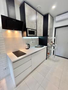 een witte keuken met een wastafel en een magnetron bij Апартаменты в Аркадии - Arcadia Sky Apartments in Odessa