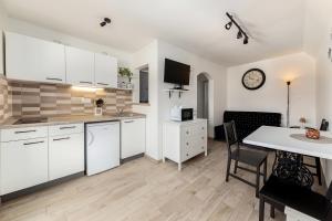 een keuken met witte kasten en een eetkamer bij Pod Koblo Bohinj Apartments in Bohinj