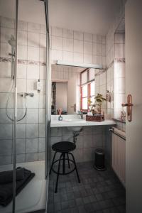 a bathroom with a sink and a shower and a stool at Sommers Hotel Altes Posteck in Reichenbach im Vogtland