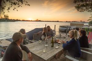 un groupe de personnes assises à une table sur un bateau dans l'établissement Pean-buiten Waterlodges, à Nes