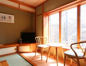 Zimmer mit einem Tisch, Stühlen und einem Fenster in der Unterkunft Ryosha Tsukiakari in Yamanakako