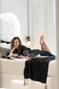 a woman laying on a bed reading a book at Anatoli Hotel in Naxos Chora