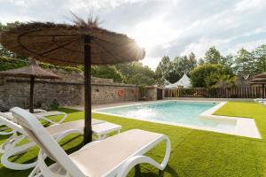 a pool with two chairs and an umbrella and a lawn at Jardines Villaverde in Villaverde de Pontones