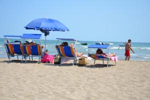 un gruppo di persone seduti su sedie a sdraio in spiaggia di Happy Camp mobile homes in Villaggio Camping Baia Domizia a Baia Domizia