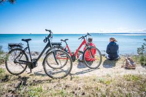 Eine Frau und zwei Fahrräder am Strand geparkt in der Unterkunft Hotel Mukran in Sassnitz