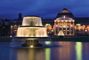 une fontaine devant un bâtiment la nuit dans l'établissement IntercityHotel Wiesbaden, à Wiesbaden