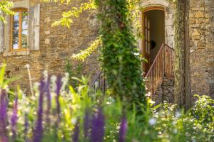 une maison en pierre avec un escalier et des fleurs devant elle dans l'établissement Maison d'Hôtes Mas de la Chadenede, à Lagorce