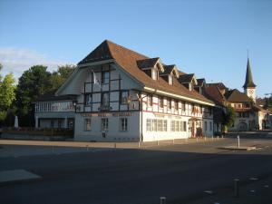 un grand bâtiment blanc avec un toit marron dans une rue dans l'établissement Hotel & Restaurant Sternen Köniz bei Bern, à Berne