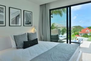 1 dormitorio con cama grande y ventana grande en Rêve de Saint Barth - Vue Mer - Piscine Chauffée & Jacuzzi, en Gustavia