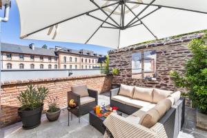 a patio with a couch and chairs and an umbrella at Maison Sévigné - Le calme du Thabor et la proximité du centre ville in Rennes