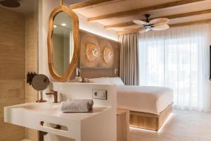 um quarto com uma cama, um lavatório e um espelho em Lago Resort Menorca - Suites del Lago Adults Only em Cala'n Bosch