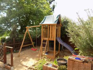 a wooden playground with a swing and a slide at ElbPension & Ferienwohnung Sächsische Schweiz in Pirna