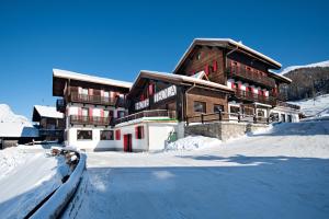 un gran edificio en la nieve con una carretera delante en Hotel Teola, en Livigno