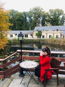 a woman sitting on a bench next to a table at Auberge du Manet in Montigny-le-Bretonneux