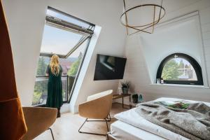 Una mujer con un vestido verde parada en una habitación con ventana en THE HEARTS HOTEL - dein Boutique- und Event-Resort, en Braunlage