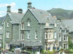 un grand bâtiment gris avec une montagne en arrière-plan dans l'établissement Keswick Park Hotel, à Keswick