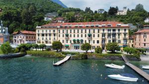 una città con barche in acqua di fronte agli edifici di Grand Hotel Menaggio a Menaggio