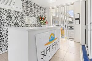 a white kitchen with black and white wallpaper at Surf Beach Motel Coffs in Coffs Harbour