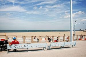 Un uomo seduto su una panchina in spiaggia di Beach House Rodine - free parking & bikes a Scheveningen