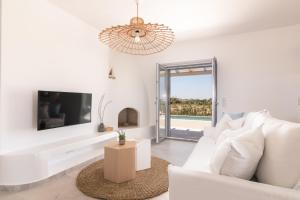 Isalos Villas Naxos في ناكسوس تشورا: غرفة معيشة بيضاء مع أريكة بيضاء وتلفزيون