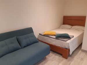 um pequeno quarto com uma cama e um sofá em Logement proche Lyon-aéroport-Centrale Bugey em Dagneux