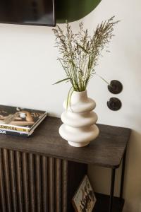 a white vase with flowers on a table at Angelus Apartments in Kraków