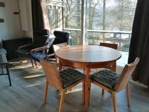 een houten tafel en stoelen in een kamer met een raam bij Au repos de Zoé in Waulsort