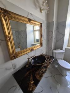 a bathroom with a gold mirror and a sink at Apartmány Svätá Barborka in Banská Štiavnica