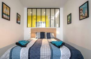 Un dormitorio con una cama con almohadas azules y una ventana en Chez Emile Le Jaune Vendée - T2 renové - Terrasse, en Niort