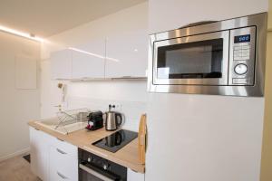 cocina blanca con microondas y fregadero en Chez Emile Le Jaune Vendée - T2 renové - Terrasse, en Niort