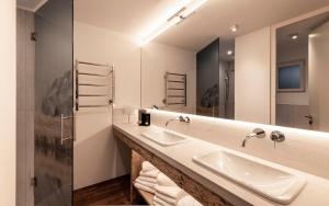 un bagno con due lavandini e un grande specchio di Bellevue Bruneck - Suites & Lofts a Brunico