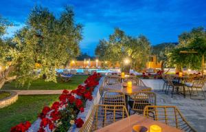 un patio con mesas, sillas y flores rojas en Nefeli Fresh Hotel by Del Mare, en Skala Rachoniou