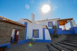 una casa azul y blanca con el sol en el cielo en Ares do Monte - Turismo Rural, en Cercal