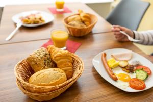 un tavolo con un cesto di prodotti per la colazione e succo d'arancia di Hotel Quellenhof a Baden-Baden