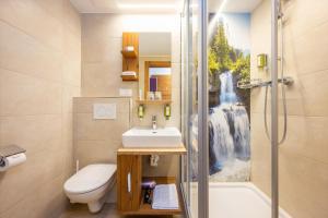 a bathroom with a sink and a shower with a waterfall mural at Hotel Alpina in Obertauern