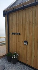 um barracão de madeira com dois vasos de plantas à sua frente em Cottages by the Sea em Sørvágur