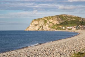 een rotsachtig strand met een berg op de achtergrond bij The County Hotel in Llandudno