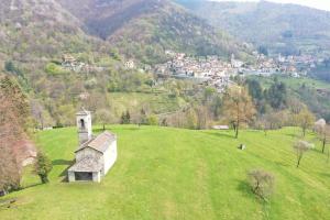 um pequeno edifício numa colina relvada com uma cidade em Bed and Breakfast Chiarina em Mendrisio