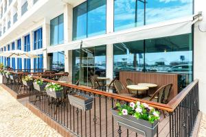 einen Balkon eines Restaurants mit Tischen und Stühlen in der Unterkunft AP Eva Senses in Faro