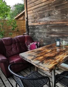 einen Holztisch auf einer Terrasse mit einem Sofa in der Unterkunft Green Garden house in Jūrmala