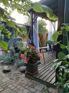 eine Holzterrasse mit Pflanzen und einem Regenschirm in der Unterkunft Green Garden house in Jūrmala