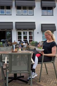 een vrouw aan een tafel met een kom eten bij Hotel VILLA GROET in Avenhorn