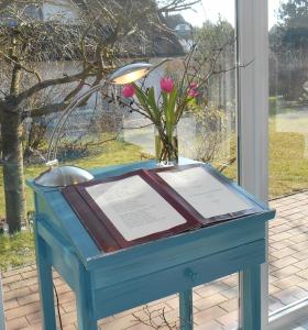 una mesa azul con una placa y un jarrón de flores en Landhotel Kastanienallee Putbus, en Putbus