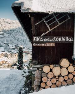 um edifício com uma pilha de troncos na neve em Hotel Mas de la Coutettaz, The Farmhouse em Morzine