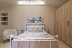 een slaapkamer met een wit bed en een stoel bij Milk and Honey Residence in Zakynthos