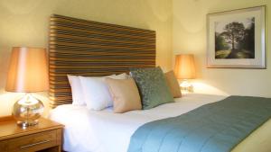 a bedroom with a bed with two lamps on a table at Marwell Hotel - A Bespoke Hotel in Winchester